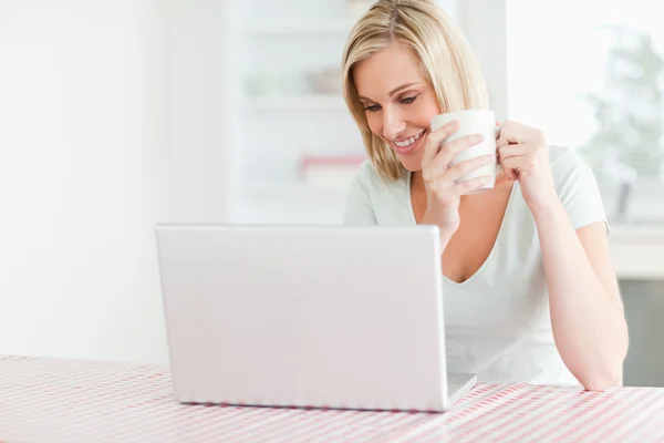 Close up of a woman holding coffee looking at the laptop in fron — Stock Photo, Image