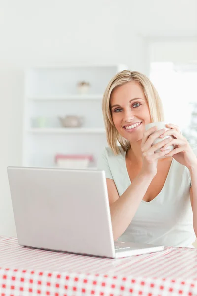 Close up de uma mulher segurando xícara de café com laptop na frente o — Fotografia de Stock