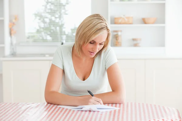 Женщина, сидящая за столом, пишет письмо — стоковое фото