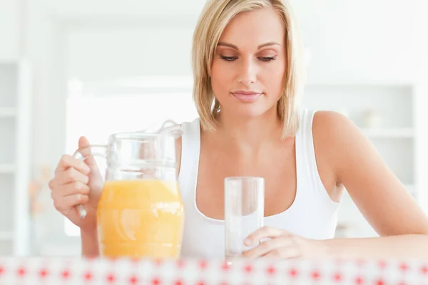 Kobieta siedzi przy stole z soku pomarańczowego i gla z bliska — Zdjęcie stockowe