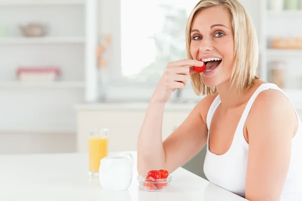 Młoda kobieta siedzi przy stole jeść truskawki — Zdjęcie stockowe