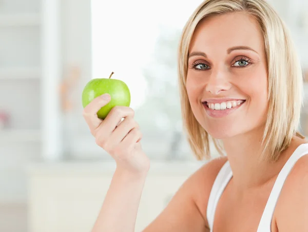 Young woman holding a green apple looking into camera — Stock Photo, Image