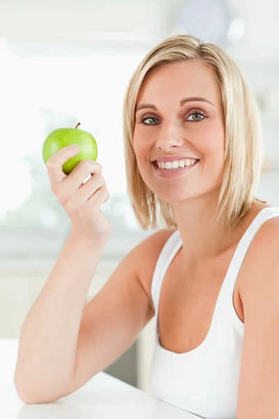 Νέα χαμογελαστό γυναίκα που κρατά ένα πράσινο μήλο εξετάζει τη φωτογραφική μηχανή — Φωτογραφία Αρχείου