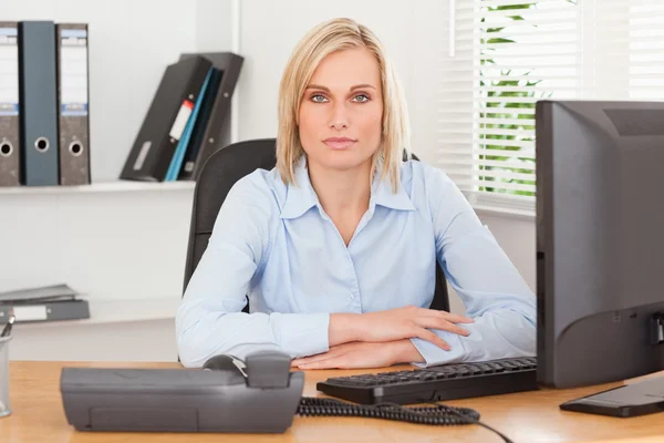Ernste Frau sitzt hinter einem Schreibtisch — Stockfoto