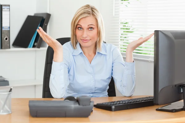 Junge blonde Frau sitzt hinter Schreibtisch und hat keine Ahnung, was sie tun soll — Stockfoto