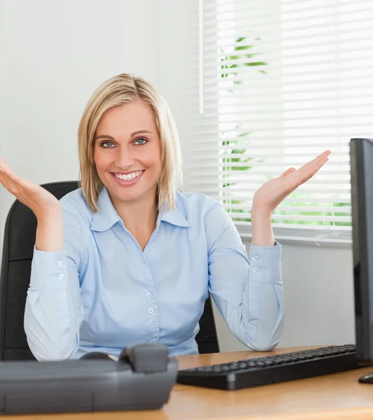 Χαμογελαστή γυναίκα που κάθεται πίσω από το γραφείο δεν έχουν ιδέα τι να κάνει για ν — Φωτογραφία Αρχείου
