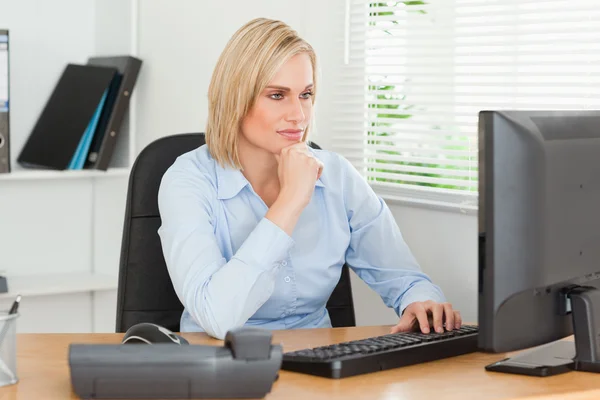 Arbeitende ernsthafte Frau vor einem Bildschirm, der sie ansieht — Stockfoto