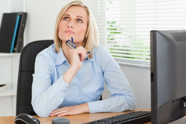 Thinking beautiful woman behind a desk looking at the ceiling — Stock Photo, Image