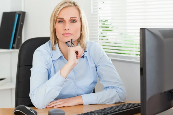 Serious thoughtful looking woman behind her desk — Stock Photo, Image