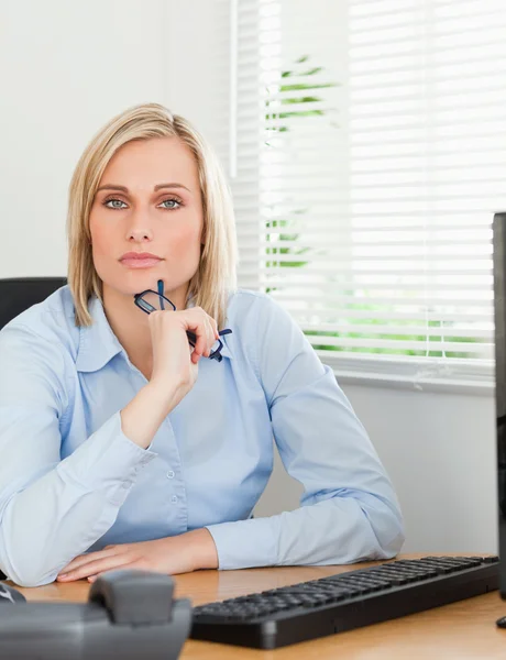 Serious thoughtful looking woman behind her desk looking into ca — Stock Photo, Image