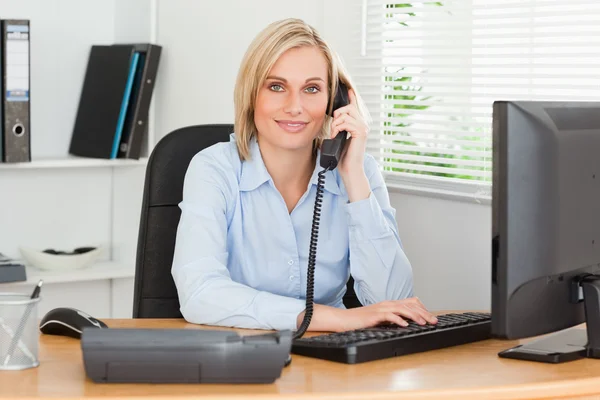 Mujer de negocios sonriente en el teléfono mirando a la cámara — Foto de Stock