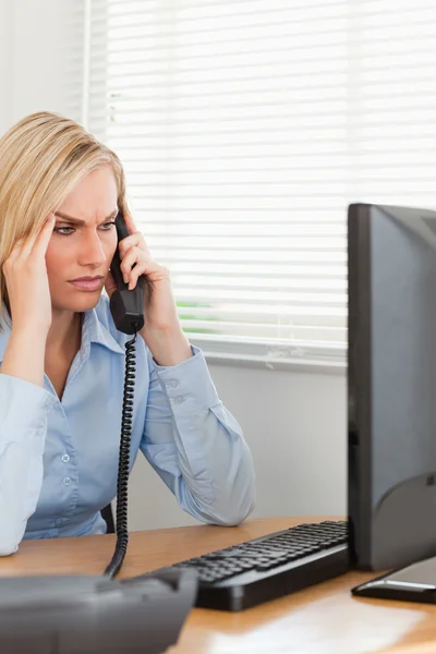 Деловая женщина по телефону смотрит на экран во время головной боли — стоковое фото