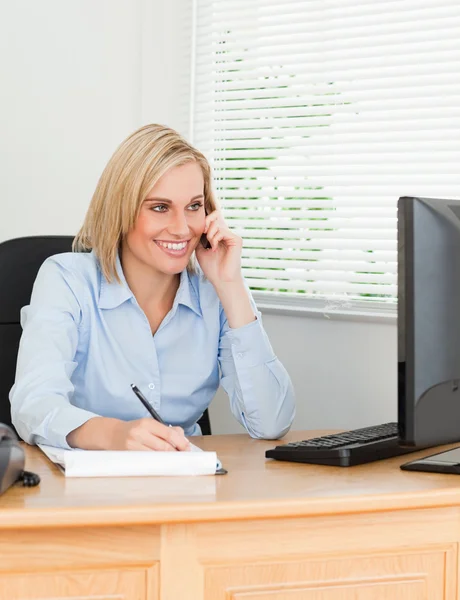 Cute businesswoman on mobile writing something down looks at her — Stock Photo, Image