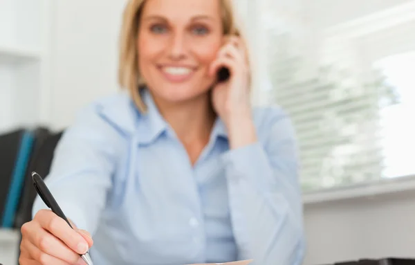 Cute businesswoman on mobile noting something looks into camera — Stock Photo, Image