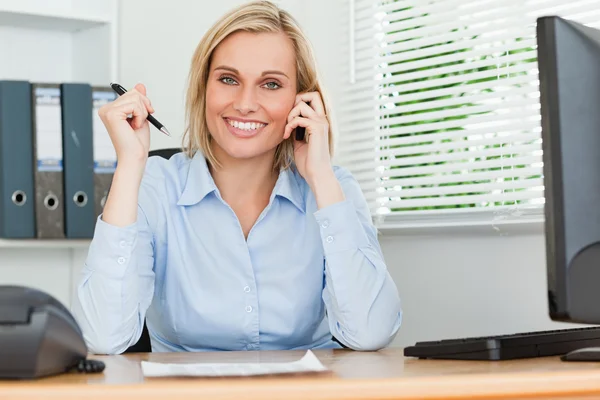 Portrait of a businesswoman smiling into camera with pen in hand — Stock Photo, Image