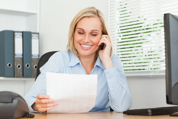 Portrait of a businesswoman reading a letter while phoning — Stock Photo, Image