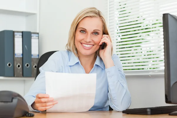 Portrait of a businesswoman looking up from a letter while phoni — Stock Photo, Image