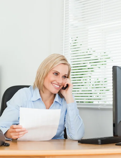 Mujer de negocios sonriendo en la pantalla mientras llama y sostiene un pape — Foto de Stock