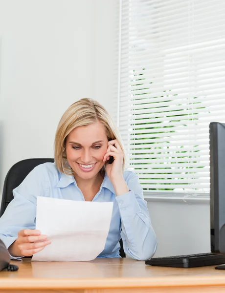 Mulher de negócios telefonando e reeding um papel — Fotografia de Stock