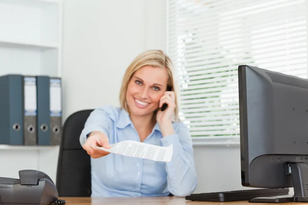 Businesswoman phoning and passing a paper looks into camera — Stock Photo, Image