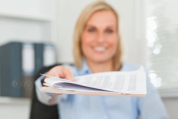 Lächelnde Geschäftsfrau reicht einen Zettel und blickt in die Kamera — Stockfoto