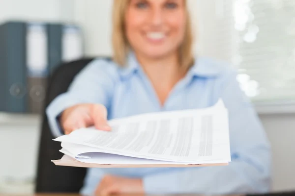 Smiling blonde businesswoman passing a paper looks into camera — Stock Photo, Image