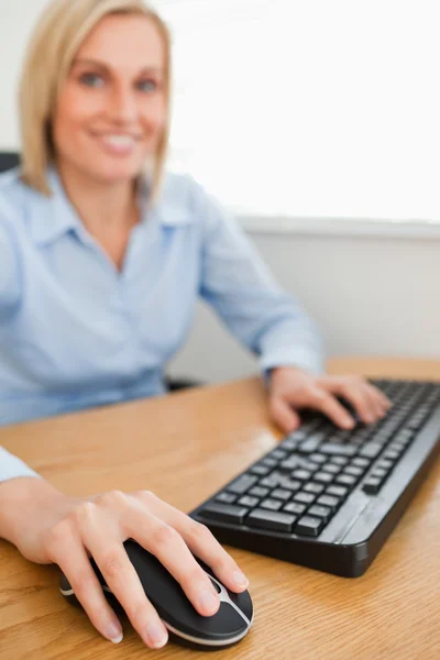 Блондинка улыбается бизнесвумен с руками на мышке и клавиатуре — стоковое фото