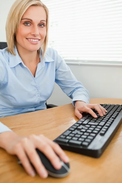 Donna d'affari sorridente con mani su mouse e tastiera — Foto Stock