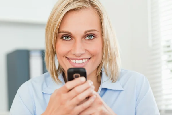 Mulher sorridente com celular olhando para a câmera — Fotografia de Stock