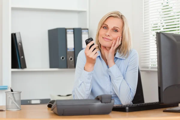 Smiling blondebusinesswoman with mobile looking into camera — Stock Photo, Image