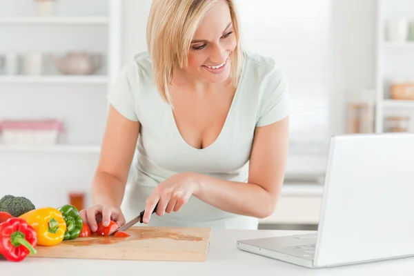 Woman enjoying cooking looking for a recipe on the laptop — Stock Photo, Image