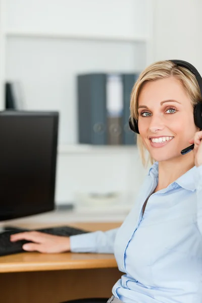 Close up van een glimlachende blonde zakenvrouw met hoofdtelefoon werken — Stockfoto