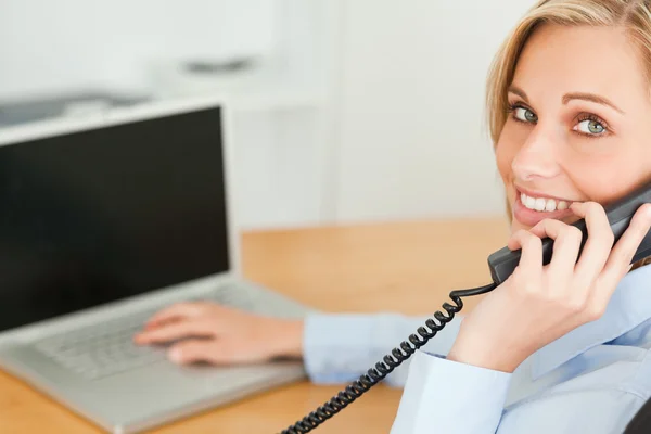 Junge Geschäftsfrau lächelt am Telefon in die Kamera — Stockfoto
