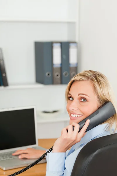 Mulher de negócios loira sorrindo para a câmera enquanto no telefone — Fotografia de Stock