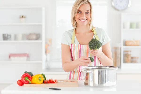 Kobieta gotowania brokułów wygląda do aparatu — Zdjęcie stockowe