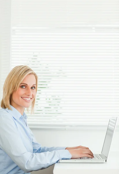Gorgeous smiling businesswoman working on laptop looking into ca — Stock Photo, Image