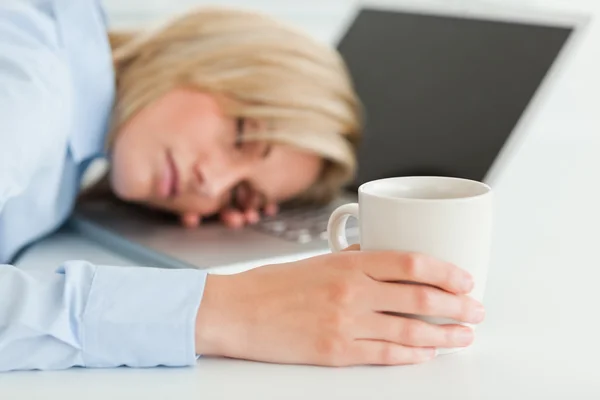 Wspaniała kobieta śpi na jej laptopie trzyma kubek kawy — Zdjęcie stockowe