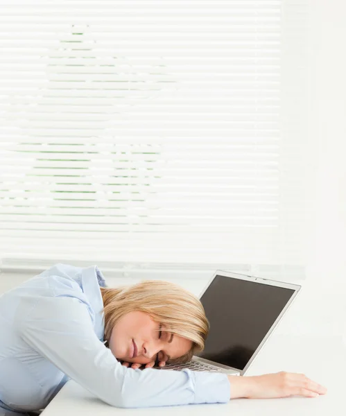 Linda mujer de negocios rubia durmiendo en su portátil sosteniendo taza o — Foto de Stock