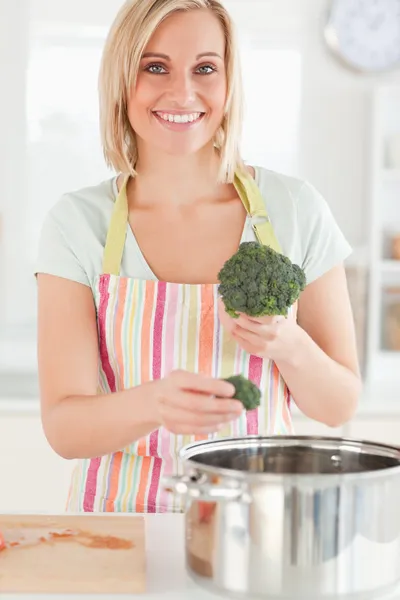 Close up of a woman cooking broccoli looks into the camera — Stock Photo, Image