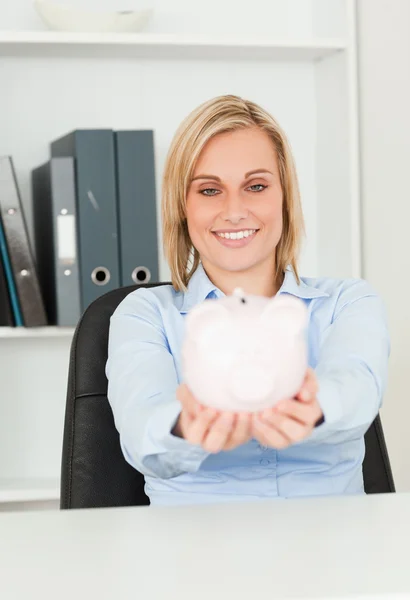 Cute blonde businesswoman holding a piggy bank — Stock Photo, Image