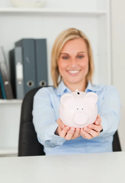 Gorgeous blonde businesswoman holding a piggy bank — Stock Photo, Image