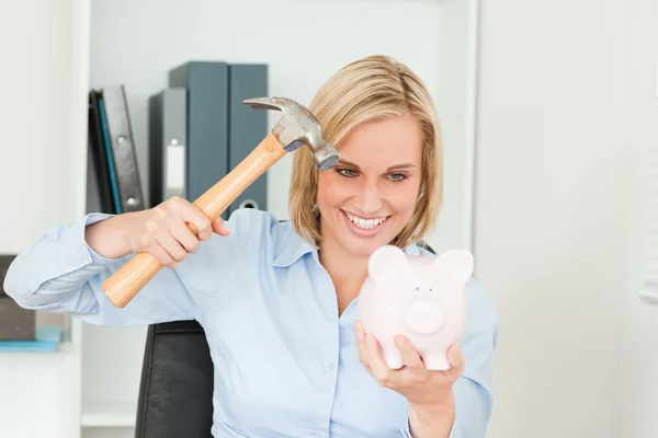 Smiling blonde woman wanting to destroy her piggy bank — Stock Photo, Image