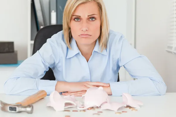 Sad woman sitting in front of an shattered piggy bank with less — Stock Photo, Image