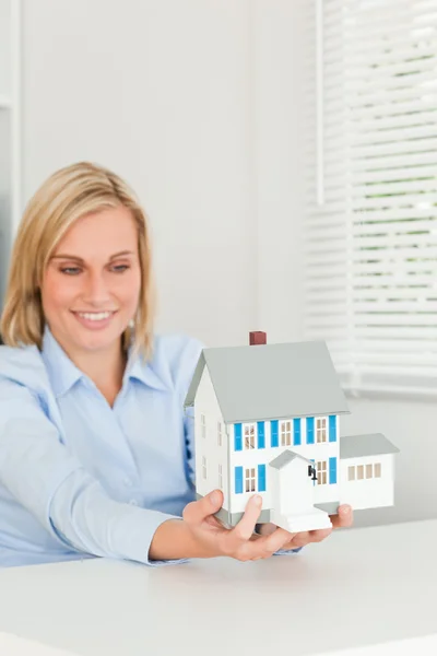 Uśmiechnięta kobieta pokazano model domu — Zdjęcie stockowe