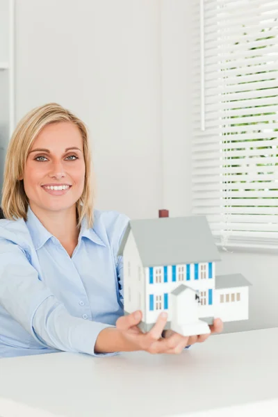 Vacker affärskvinna visar modell hus ser in i kameran — Stockfoto
