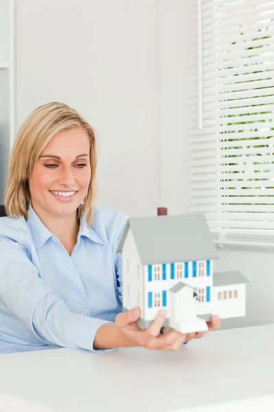 Чудова бізнес-леді показує модель будинку, дивлячись на нього — стокове фото