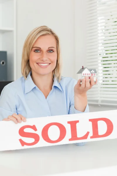 Gorgeous blonde businesswoman showing miniature house and SOLD s — Stock Photo, Image
