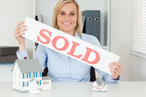 Blond affärskvinna visar såld underteckna tittar in i kameran — Stockfoto