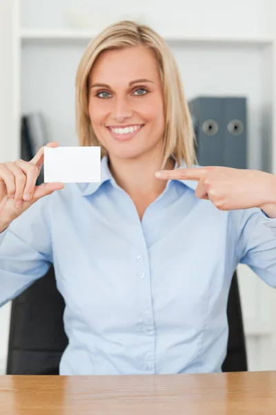 Улыбающаяся блондинка-бизнесвумен, указывающая на открытку, не смотрит на нее — стоковое фото