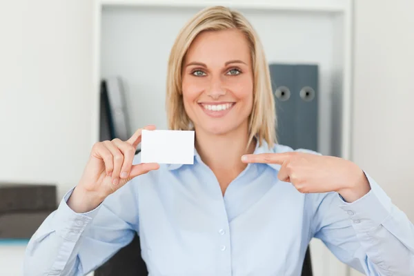 Businesswoman pointing at a card looks itno camera — Stock Photo, Image
